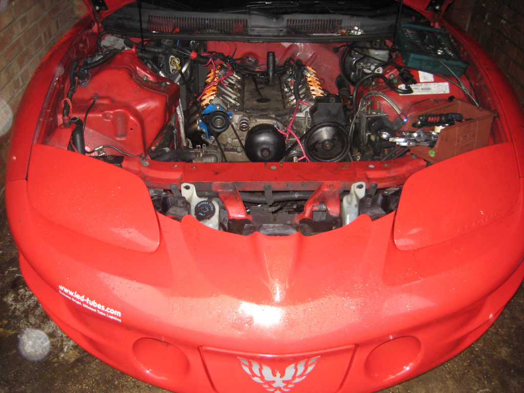 The engine bay of my LS1. Rocker covers/coil packs removed, radiator removed. Easier to work on. Looks like the heads will be coming off tommorow.